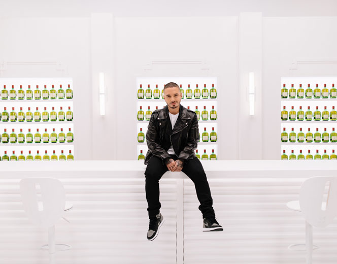 Columbian singer J Balvin sitting in front of a Buchanan’s Scotch Whisky display as part of a campaign created by the HUNTER integrated marketing and PR firm in NYC.